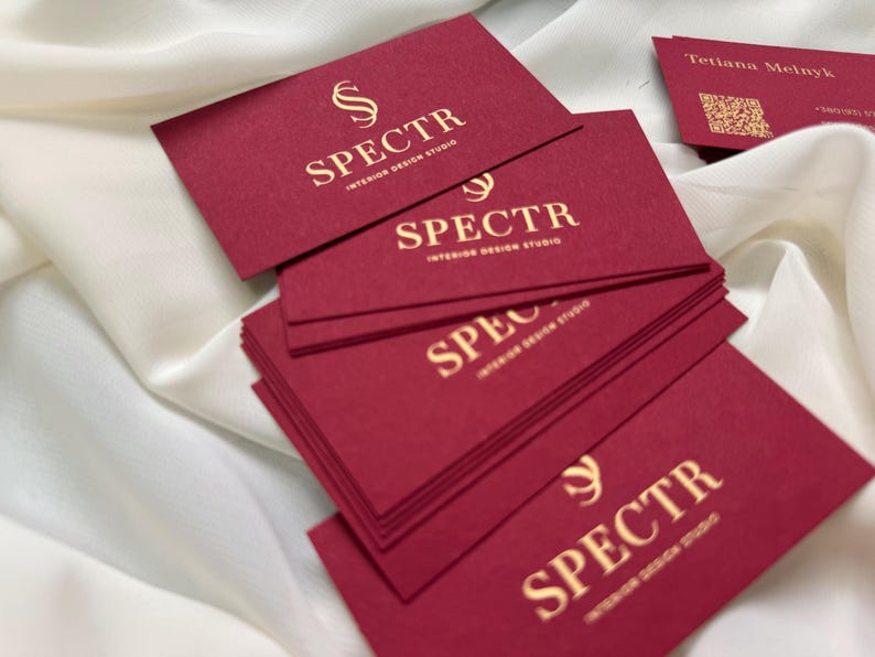 May include: A stack of red business cards with gold lettering. The text on the cards reads "SPECTR INTERIOR DESIGN STUDIO".
