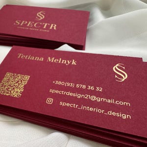 May include: Red business cards with gold lettering. The cards feature the name Tetiana Melnyk, a phone number, email address, and the text "spectr_interior_design".