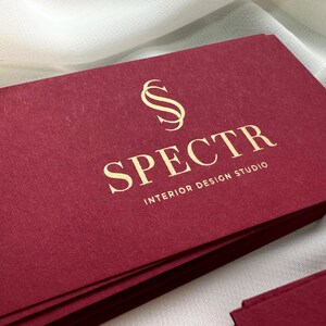 May include: A stack of burgundy business cards with gold lettering. The logo is a stylized letter "S" and the text reads "SPECTR INTERIOR DESIGN STUDIO".
