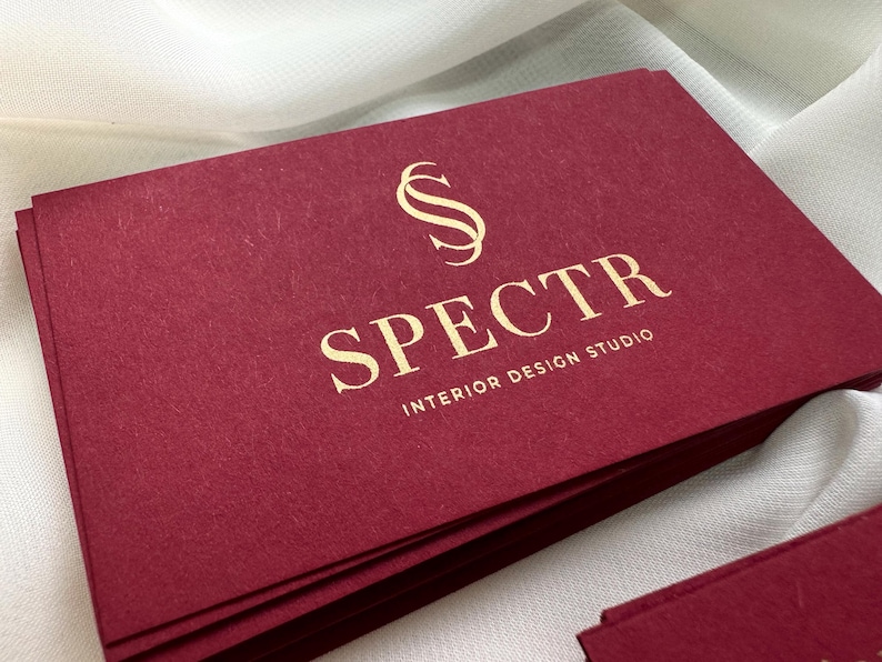 May include: A stack of burgundy business cards with gold lettering. The logo is a stylized letter "S" and the text reads "SPECTR INTERIOR DESIGN STUDIO".