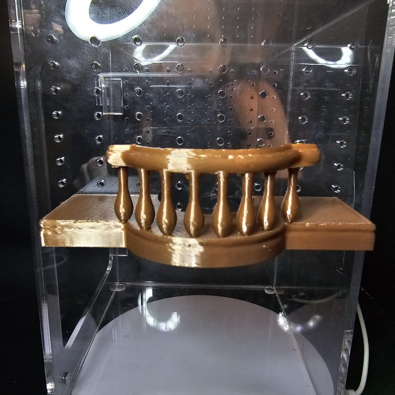 Puede incluir: Una barandilla de balc&oacute;n de pl&aacute;stico marr&oacute;n impresa en 3D con una plataforma plana. La barandilla est&aacute; hecha de un material liso, similar al pl&aacute;stico, y tiene una forma redondeada. La plataforma es plana y tiene una superficie texturizada.