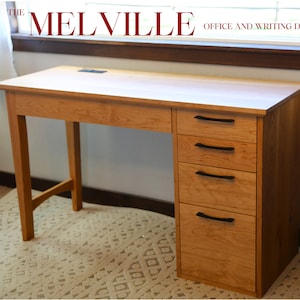 May include: A light wood office desk with four drawers and black drawer pulls. The desk has a simple design with straight lines and a light wood finish. The desk is sitting on a light beige rug in front of a window.