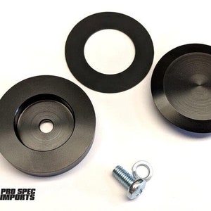 Puede incluir: Componentes metálicos negros, que incluyen dos piezas circulares, un anillo y un perno con un ojal. Las piezas tienen un acabado mate y están dispuestas sobre una superficie blanca. El logotipo "PRO SPEC IMPORTS" es visible.