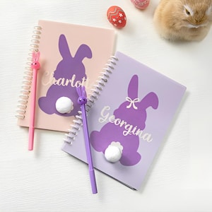 May include: Two purple and pink spiral notebooks with bunny silhouettes and the names Charlotte and Georgina. Each notebook comes with a purple bunny pen.