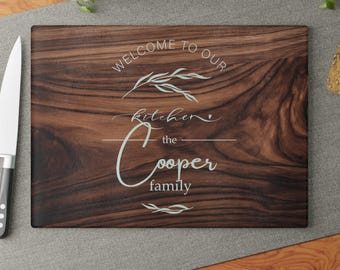 May include: A brown wooden cutting board with the text "Welcome to our kitchen the Cooper family" engraved on it.