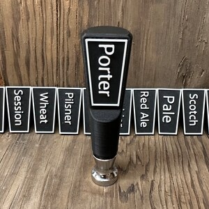 May include: Black beer tap handle with the word "Porter" in white lettering on a white background. The handle is surrounded by 12 black and white beer style labels, including IPA, Blonde, Session, Wheat, Pilsner, Red Ale, Pale, Scotch, Barley, Brown, and Stout.