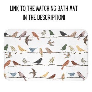 K&ouml;nnte beinhalten: Eine wei&szlig;e Badematte mit einem sich wiederholenden Muster aus bunten V&ouml;geln auf einem Drahtzaun. Die V&ouml;gel sind aus Patchwork-Stoff mit floralen und geometrischen Mustern.