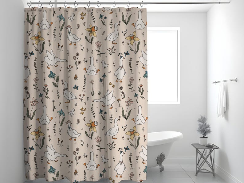 May include: A beige shower curtain with a repeating pattern of white geese, flowers, and leaves. The geese are in various poses, some are standing, some are walking, and some are swimming. The flowers are in shades of yellow, orange, and pink. The leaves are in shades of green and brown.