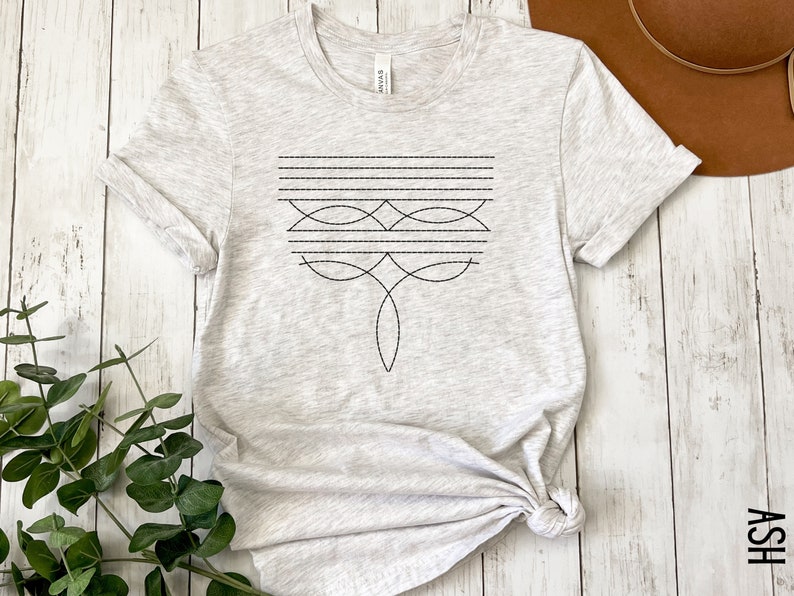 Puede incluir: Una camiseta gris jaspeada con un dise&ntilde;o geom&eacute;trico negro en la parte delantera. El dise&ntilde;o presenta una serie de l&iacute;neas y curvas.