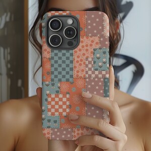 May include: A phone case with a patchwork design featuring various colors and patterns, including pink, orange, blue, and green. The case has a camera cutout and a geometric pattern.