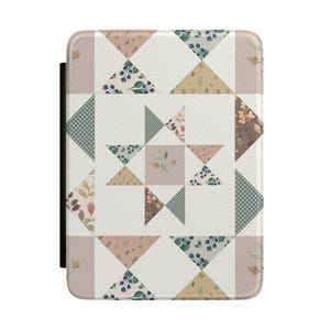 May include: A rectangular e-reader cover featuring a patchwork quilt design with a central star motif. The pattern consists of triangles and squares in muted tones of sage green, dusty pink, cream, and brown, decorated with botanical prints and dots.