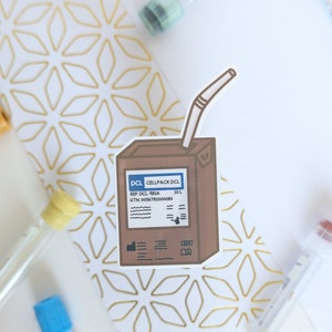 Peut inclure: Une boîte en carton marron avec une paille qui sort du dessus. La boîte porte l'inscription "CELLPACK DCL" et "REF DCL-981A". La boîte est un autocollant sur un fond blanc.