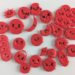 May include: A collection of 25 red, round, plastic buttons with various black cartoon faces. Each button has a different expression, including happy, sad, angry, and surprised.