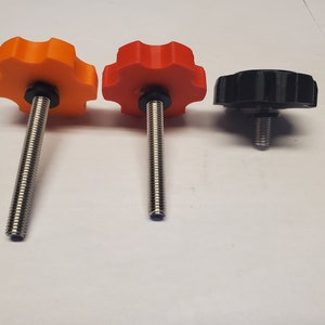 May include: Three knobs with threaded shafts. The knobs are made of plastic and are orange, red, and black.