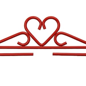 May include: A red metal decorative wall hanging with a heart-shaped design in the center. The piece features a horizontal bar with a looped end on each side, and decorative swirls. The heart is formed by two curved lines.