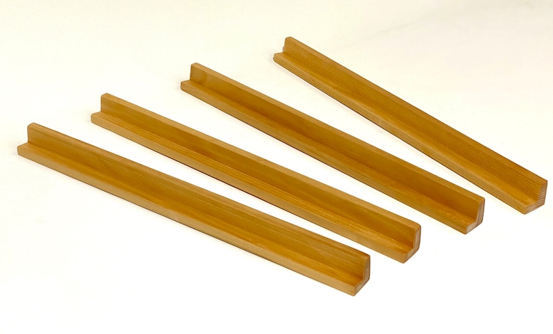 May include: Four wooden tile racks, each with a U-shaped groove, are arranged in a staggered pattern on a white surface.
