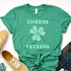 May include: Green t-shirt with a four-leaf clover and the text "CHEERS FECKERS" in white.