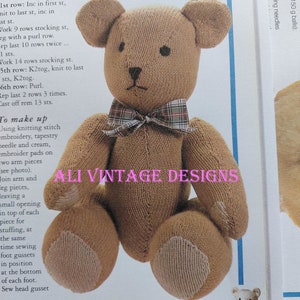 May include: A knitted brown teddy bear with a red and black plaid bow tie. The bear is sitting on a white background with the text "ALI VINTAGE DESIGNS" and "MISTER BEAR".