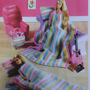 Puede incluir: Un juego de pijamada para muñecas de moda, con una muñeca rubia, una silla rosa y una guitarra. El juego incluye una manta a rayas, una almohada y un saco de dormir en colores pastel. Altura aproximada 28 cm.