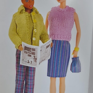 May include: Two dolls dressed in knitted outfits. One doll wears a yellow cardigan, plaid pants, and holds a newspaper. The other doll wears a pink top, a striped skirt, and carries a blue purse. Both dolls have blonde hair.