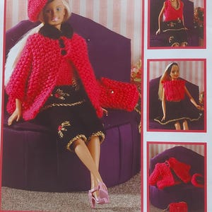 May include: A pink knitted doll outfit with a matching beret, a black skirt with gold accents, and a pink knitted handbag. The doll is sitting on a purple chair. The outfit is called "Disco Diva".