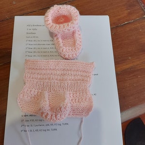 Può includere: Scarpine per neonato in maglia rosa con istruzioni per realizzarle. Le istruzioni includono l'avvio di 43 punti e l'aumento di punti in ogni riga.