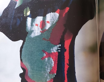 May include: A woman wearing a red hat and gloves, a red scarf, and a blue sweater with a red and white koala design. The sweater has a high neck and long sleeves. The woman is wearing a red skirt.