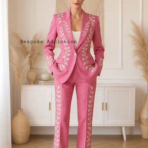 May include: A pink suit with floral embroidery. The suit includes a blazer with pockets and matching pants. The text "Bespoke Addiction" is visible on the image. The outfit is worn with nude heels.