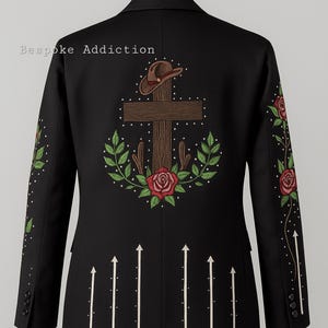 Puede incluir: Chaqueta negra con bordados. La espalda presenta una cruz, sombrero de vaquero, rosas y hojas. Flechas blancas apuntan hacia arriba. Las mangas tienen patrones florales y de puntos. El texto "Bespoke Addiction" es visible.