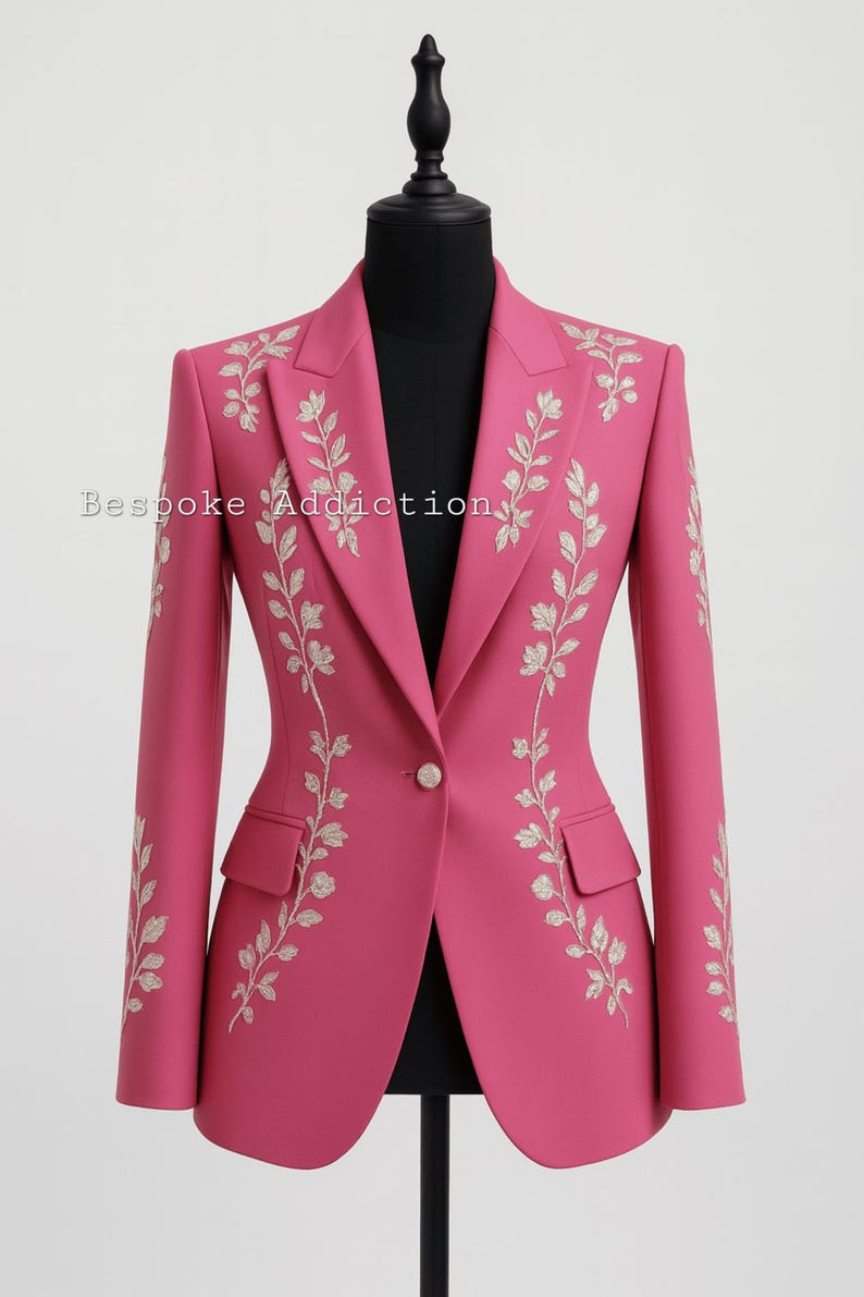 May include: A vibrant pink blazer with intricate floral embroidery. The jacket features a single-button closure, two front pockets, and long sleeves. The text "Bespoke Addiction" is visible on the left side. This tailored blazer is a stylish addition to any wardrobe.