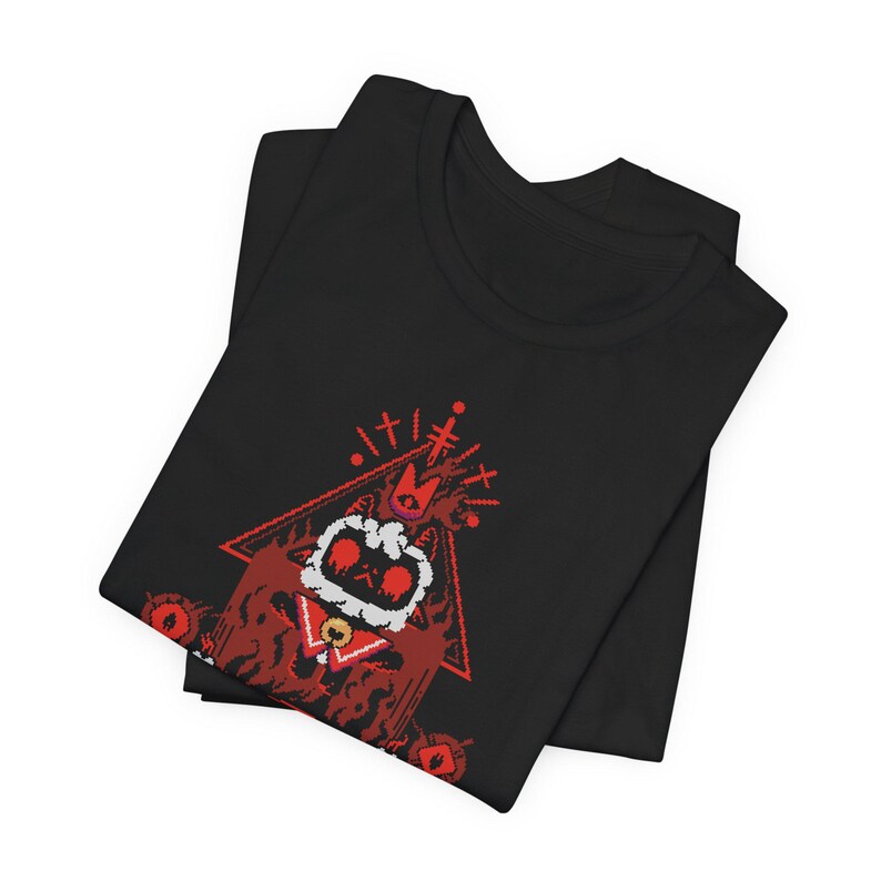 May include: Black t-shirt with a red pixelated illustration of a creature wearing a crown and standing in a triangle. The creature has large eyes and is surrounded by flames.