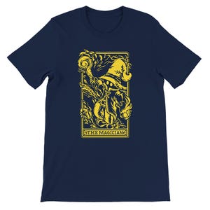 Puede incluir: Una camiseta azul marino con un gr&aacute;fico amarillo de un personaje de mago de un videojuego. El gr&aacute;fico est&aacute; en un marco de tipo tarjeta con el texto "THE MAGICIAN".