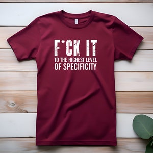 May include: A maroon t-shirt with the text "F*CK IT TO THE HIGHEST LEVEL OF SPECIFICITY" printed in white.