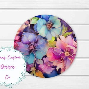May include: A round, colorful floral design with blue, pink, purple, and green flowers. The flowers have gold accents and are on a dark blue background.