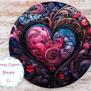 May include: A round, black background with a large, pink and blue heart-shaped design. The heart is made up of intricate swirls and floral patterns. The background is filled with smaller, swirling patterns in shades of purple, blue, and gold.
