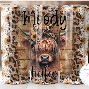 Könnte beinhalten: Ein Edelstahlbecher mit einer braunen Kuh mit einer Sonnenblumenkrone und einem Leopardenmuster im Hintergrund. Der Text "Moody Heifer" ist auf den Becher gedruckt.