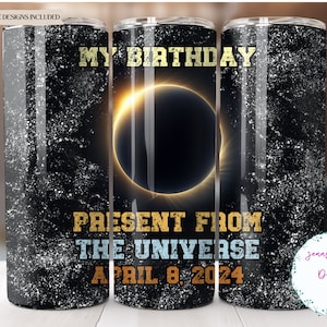 May include: A black and white tumbler with a galaxy design and gold lettering. The text reads "My Birthday Present From The Universe April 8, 2024".
