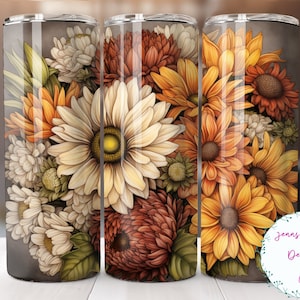 May include: A set of three stainless steel tumblers with a floral design featuring sunflowers, mums, and daisies in shades of yellow, orange, and white. The background is a dark gray.