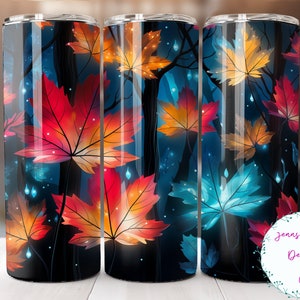May include: Three stainless steel tumblers with a colorful autumn leaf design. The leaves are glowing with a light blue, orange, and red color. The background is a dark blue.