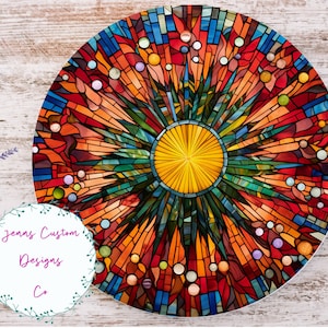 Puede incluir: Un diseño redondo de vitral colorido con un sol amarillo central. El diseño presenta una variedad de colores, incluyendo rojo, naranja, amarillo, verde, azul y morado. El vitral está colocado en un marco circular.