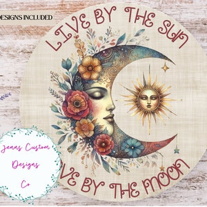 Op de afbeelding: Een ronde, beige canvas print met een halve maan en zon ontwerp. De maan is blauw en groen met een bloemenontwerp en een vrouwen gezicht. De zon is geel met een menselijk gezicht. De tekst "LIVE BY THE SUN LIVE BY THE MOON" is geschreven in rood cursief.