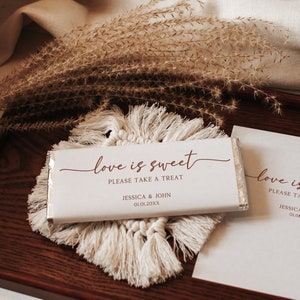 Könnte beinhalten: Weiße Schokoladentafelverpackung mit dem Text "love is sweet" in Kursivschrift. Die Verpackung enthält auch den Text "Please take a treat", "Jessica & John" und "01.01.20XX".