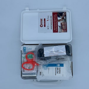 May include: A white first aid kit open to reveal a variety of medical supplies, including a tourniquet, gauze pads, and scissors. The kit is labeled with the text "STOP THE BLEED.ORG" and "ACS".