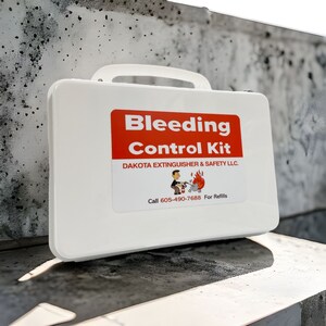 May include: White plastic first aid kit with a red label that says "Bleeding Control Kit" and the company name "Dakota Extinguisher & Safety LLC."  The label also includes a cartoon illustration of a person using a fire extinguisher and the phone number 605-490-7688.  The label says "For Refills" under the phone number.