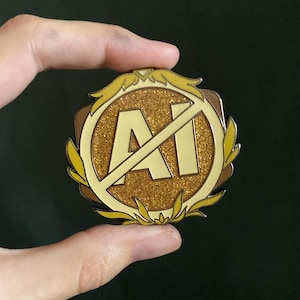 May include: A gold-colored pin with the text "AI" crossed out. The pin has a glittery center and is surrounded by a yellow border with leaf accents. The pin is round and has a shiny finish.