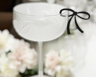 Peut inclure: Une flûte à champagne en verre transparent avec un nœud en papier noir attaché autour du pied.