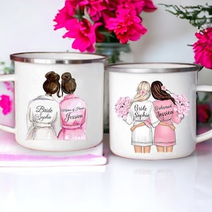 Könnte beinhalten: Zwei weiße Emailletassen mit schwarzem Rand. Die Tassen zeigen eine handgezeichnete Illustration von zwei Frauen in Roben. Eine Tasse sagt "Bride Sophie" und "Maid of Honor Jessica". Die andere Tasse sagt "Bride Sophie" und "Bridesmaid Jessica".