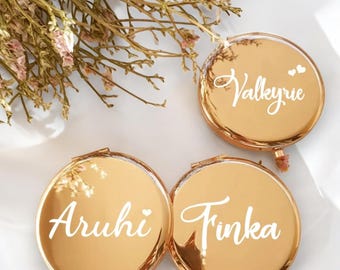 Può includere: Tre specchietti compatti dorati con nomi personalizzati: "Valkyrie", "Aruhi" e "Tinka".