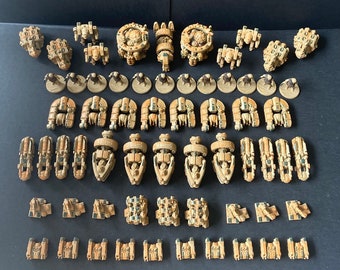 May include: A collection of beige and brown plastic miniature spaceships and vehicles. The miniatures are arranged in rows on a dark surface.