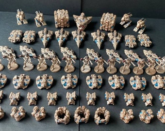 Pode incluir: Uma coleção de naves espaciais em miniatura e figuras pintadas em dourado e azul. As naves espaciais são de vários tamanhos e formas, e as figuras estão em pé sobre bases circulaires.